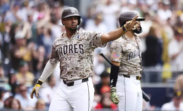 San Diego Padres' Xander Bogaerts, left, points toward first base after scoring on a single hit by Elias Diaz against the Pittsburgh Pirates in the seventh inning of a baseball game Sunday, June 1, 2025, in San Diego. (AP Photo/Derrick Tuskan)