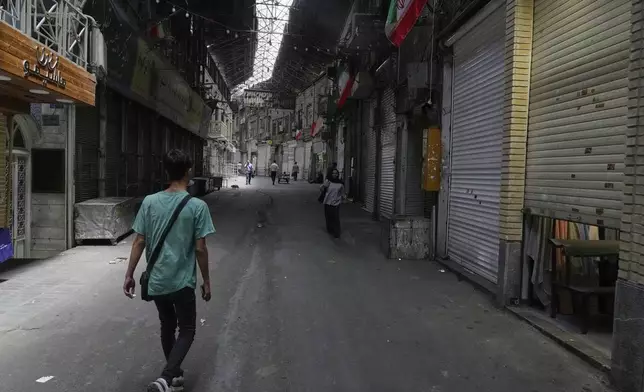 Few pedestrians walk along the historic Grand Bazaar as shops remain shuttered, in Tehran, Iran, Monday, June 16, 2025. (AP Photo/Vahid Salemi)