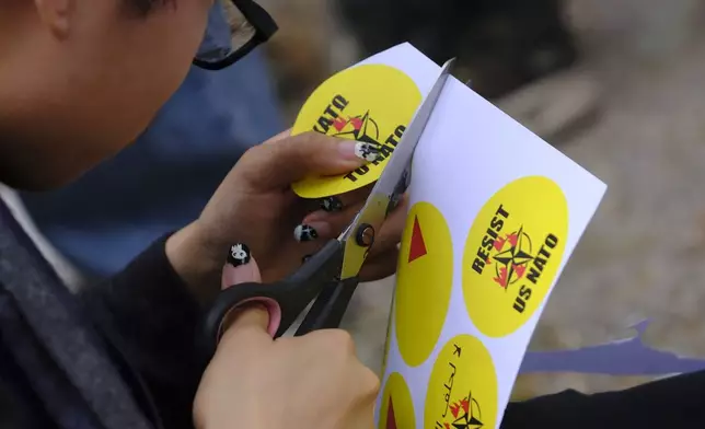 A protester cuts stickers during a rally against the NATO summit in The Hague, Netherlands, Tuesday, June 24, 2025. (AP Photo/Patrick Post)