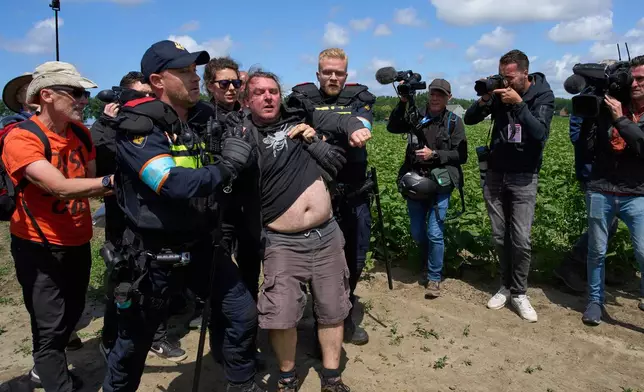 Police detain demonstrators with Extinction Rebellion who attempted to block the A44 motorway, closed off to all traffic except for arriving and departing world leaders, in Abbenes, Netherlands, Monday, June 23, 2025, for the NATO summit in The Hague. (AP Photo/Peter Dejong)