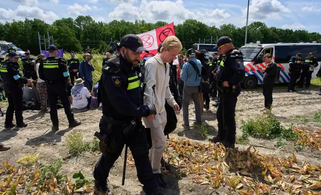 Police detain demonstrators with Extinction Rebellion who attempted to block the A44 motorway, closed off to all traffic except for arriving and departing world leaders, in Abbenes, Netherlands, Monday, June 23, 2025, for the NATO summit in The Hague. (AP Photo/Peter Dejong)