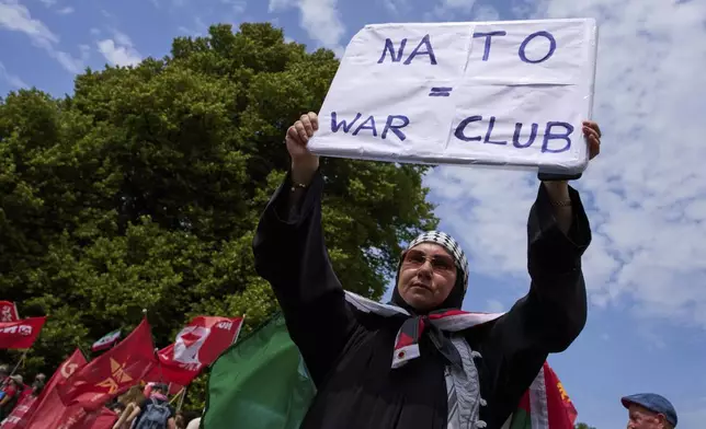 A woman holds a placard during a demonstration ahead of the NATO summit in The Hague, Netherlands, Sunday, June 22, 2025. (AP Photo/Peter Dejong)