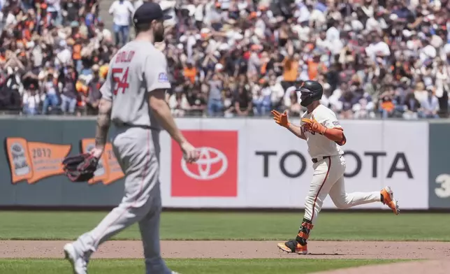 San Francisco Giants' Casey Schmitt, right, gestures after hitting a home run off of Boston Red Sox pitcher Lucas Giolito, left, during the fifth inning of a baseball game in San Francisco, Sunday, June 22, 2025. (AP Photo/Jeff Chiu)