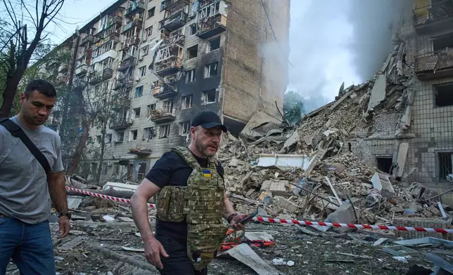 Ukraine's Interior Minister Ihor Klymenko, right, examines the site of a missile strike that ruined a residential building during Russia's massive missile and drone air attack in Kyiv, Ukraine, Tuesday, June 17, 2025. (AP Photo/Efrem Lukatsky)