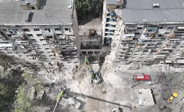 In this aerial photo provided by the Ukrainian Emergency Service, searchers sift through the wreckage on the site of Russia's Tuesday deadly missile attack that ruined a multistory residential building in Kyiv, Ukraine, Wednesday, June 18, 2025. (Ukrainian Emergency Service via AP)