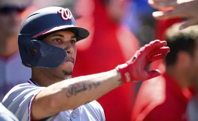 Washington Nationals' Daylen Lile is greeted by teammates after scoring during the ninth inning of a baseball game against the Los Angeles Angels, Sunday, June 29, 2025, in Anaheim, Calif. (AP Photo/William Liang)
