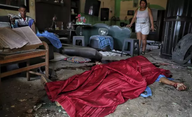 The body of Jose Carabali Galeano is covered in his living room, as his relatives look on, after a bomb exploded in Guachinte, Cauca Valley, Colombia, Tuesday, June 10, 2025. (AP Photo/Santiago Saldarriaga)