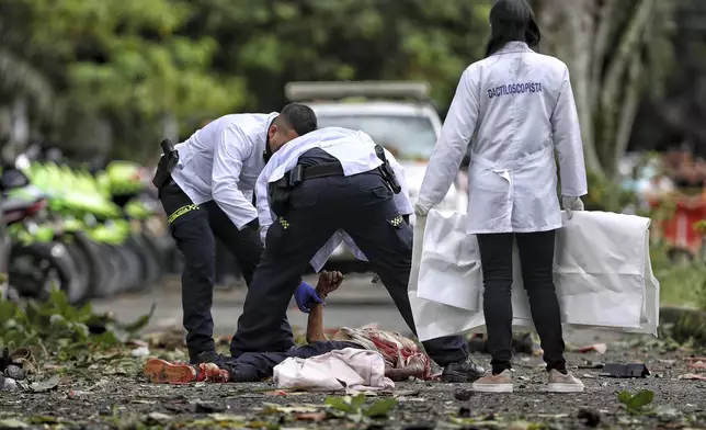 Police forensics inspect a body after a bomb explosion in Cali, Colombia, Tuesday, June 10, 2025. (AP Photo/Santiago Saldarriaga)
