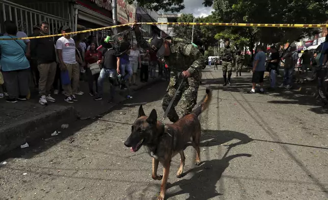 A soldier and dog enter the site where a bomb exploded in Cali, Colombia, Tuesday, June 10, 2025. (AP Photo/Santiago Saldarriaga)