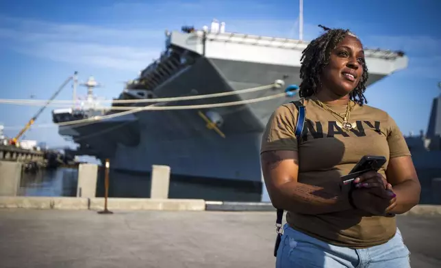 Latoya Savoy stands in front of the USS Gerald R. Ford aircraft carrier leaves Naval Station Norfolk with her daughter (unnamed), a U.S. Navy sailor who works in aviation ordinance on Tuesday, June 24, 2025, in Norfolk, Va. (AP Photo/John Clark)