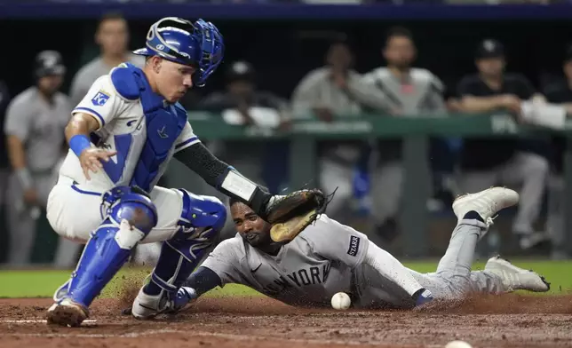 New York Yankees' Pablo Reyes, right, scores against Kansas City Royals catcher Freddy Fermin, left, in the eighth inning of a baseball game Thursday, June 12, 2025, in Kansas City, Mo. (AP Photo/Ed Zurga)