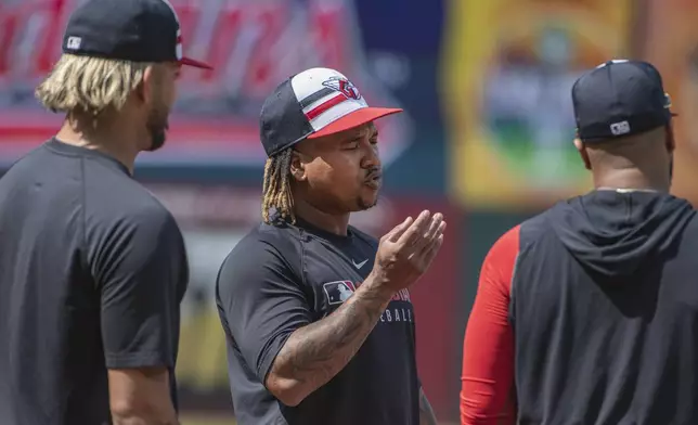 Cleveland Guardians' Jose Ramirez, center, talks with Gabriel Arias, left, and Carlos Santana, right, before a baseball game against the Cincinnati Reds, Tuesday June 10, 2025, in Cleveland. (AP Photo/Phil Long)