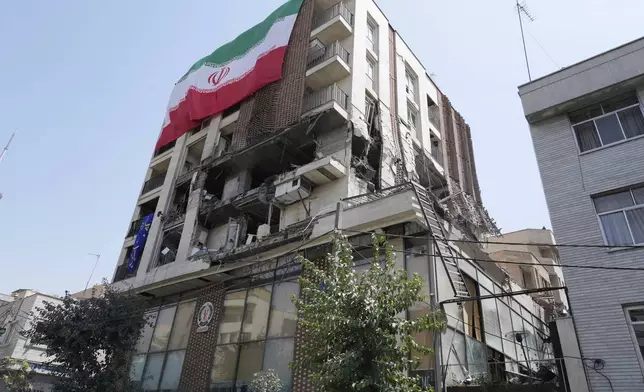 An Iranian flag hangs on a building which was hit by an Israeli strike last week, in Tehran, Iran, Wednesday, June 25, 2025. (AP Photo/Vahid Salemi)