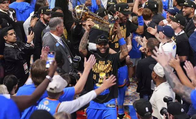 Oklahoma City Thunder forward Kenrich Williams holds up the Larry O'Brien Championship Trophy as he celebrates with his team after they won the NBA basketball championship with a Game 7 victory against the Indiana Pacers Sunday, June 22, 2025, in Oklahoma City. (AP Photo/Kyle Phillips)