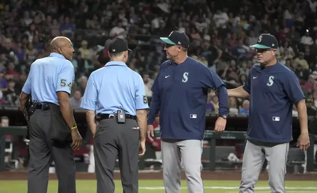 Seattle Mariners manager Dan Wilson, second right, is restrained by bench coach Manny Acta after having words with home plate umpire CB Bucknor (54) in the sixth inning during a baseball game against the Arizona Diamondbacks, Tuesday, June 10, 2025, in Phoenix. (AP Photo/Rick Scuteri)