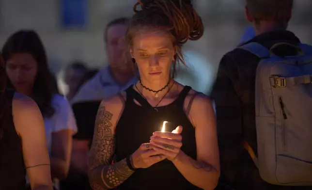 A woman holds a candle for victims of a former student who opened fire at a school, fatally wounding 10 people and injuring many others before taking his own life, in Graz, Austria, Tuesday, June 10, 2025. (AP Photo/Darko Bandic)