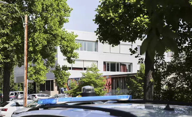 A police car stand in front of a school building after shooting at the school in Graz, Austria, Tuesday, June 10, 2025. (AP Photo/Heinz-Peter Bader)