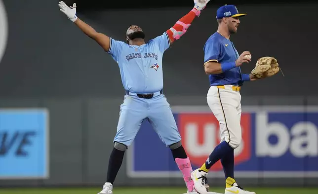 Toronto Blue Jays' Vladimir Guerrero Jr. (27), left, celebrates after hitting a double during the eighth inning of a baseball game against the Minnesota Twins, Friday, June 6, 2025, in Minneapolis. (AP Photo/Abbie Parr)