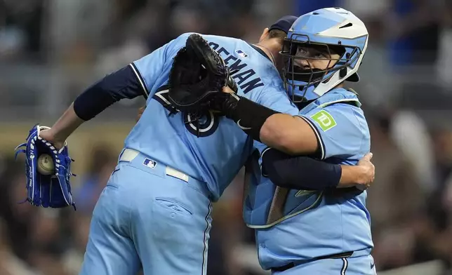 Toronto Blue Jays relief pitcher Jeff Hoffman (23), left, and catcher Alejandro Kirk (30) hug after a baseball game against the Minnesota Twins, Friday, June 6, 2025, in Minneapolis. (AP Photo/Abbie Parr)