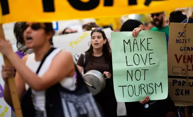 Demonstrators bang pots and shout slogans during a protest against mass tourism in Lisbon, Sunday, June 15, 2025. (AP Photo/Armando Franca)