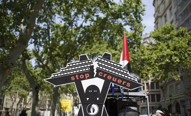 A cardboard figure of a cruise ship is photographed during a protest against overtourism in Barcelona, Spain, Sunday, June 15, 2025. (AP Photo/Pau Venteo)