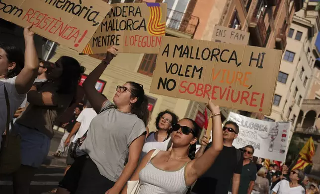 People march during a protest against overtourism in the Balearic island of Mallorca, Spain, Sunday, June 15, 2025. The placards in Mallorquin read, 'In Mallorca we want to live, not survive'. (AP Photo/Joan Mateu Parra)