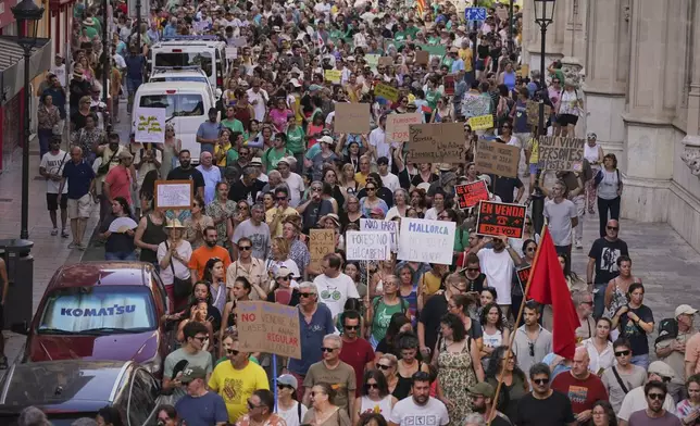 People march during a protest against overtourism in the Balearic island of Mallorca, Spain, Sunday, June 15, 2025. Signs read in mallorquin, 'For Sale'. (AP Photo/Joan Mateu Parra)