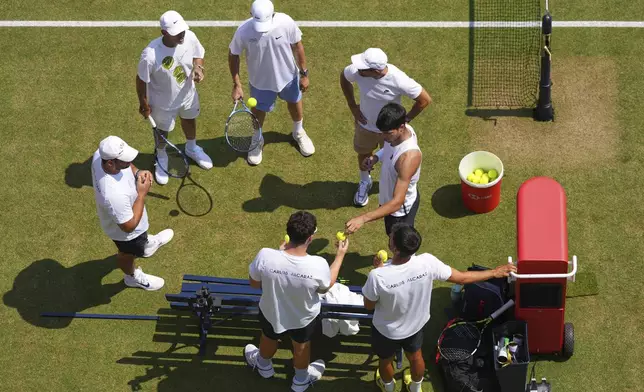 Carlos Alcaraz of Spain stands with his team during a training session at the Queen's Club Tennis Championships in London, England, Thursday, June 19, 2025. (AP Photo/Kirsty Wigglesworth)