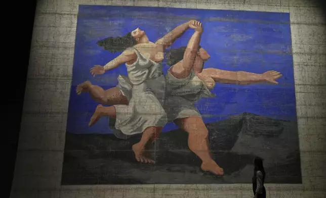 Le Train Bleu, a theatre front cloth painted by Prince Alexander Schervashidze, which is based on Pablo Picasso's "The two women running along the beach", on display at the V&amp;A Storehouse in London, Thursday, June 5, 2025. (AP Photo/Joanna Chan)