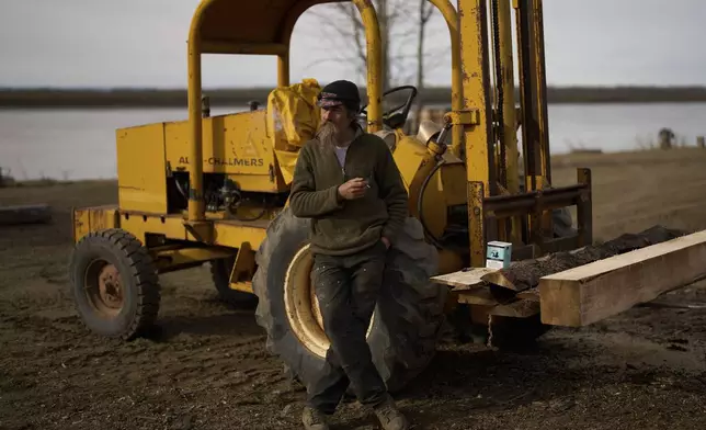 Jake Pogrebinsky smokes a cigarette during a brake from milling logs Thursday, May 22, 2025, in Galena, Alaska. (AP Photo/John Locher)
