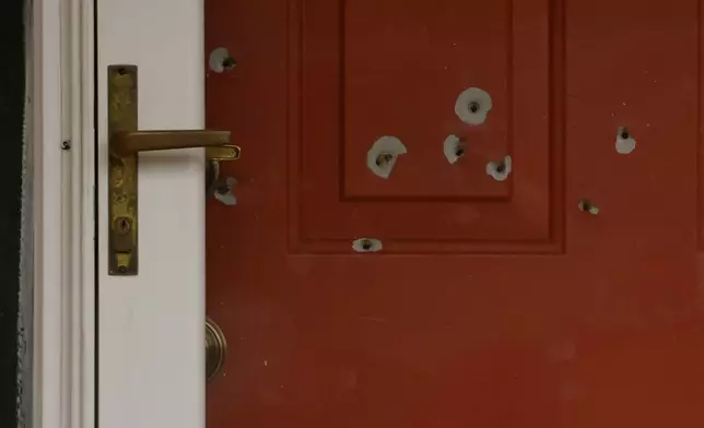 Bullet holes mark the front door of the house of Minnesota state Sen. John Hoffman and his wife who were shot earlier in the day, Saturday, June 14, 2025, in Champlin, Minn. (AP Photo/Bruce Kluckhohn)