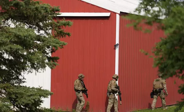 Members of law enforcement agencies search for shooting suspect, Vance Boelter, at a house Sunday, June 15, 2025, in Belle Plaine, Minn. (AP Photo/George Walker IV)