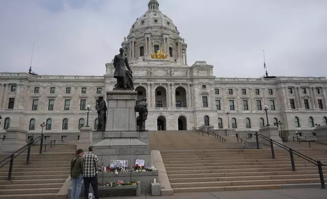 People visit a makeshift memorial for Minnesota state Rep. Melissa Hortman and her husband Mark at the state Capitol, Sunday, June 15, 2025, in St. Paul, Minn. (AP Photo/George Walker IV)