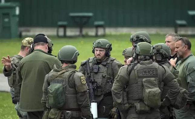 Law enforcement officers with the River Valley Tactical Team, prepare to visit the home of Vance Luther Boelter, who officials describe as a person of interest in the killing of Rep. Melissa Hortman and her husband, and the shooting of Sen. John Hoffman, near Green Isle, Minn., Saturday, June 14, 2025. (Anthony Souffle/Star Tribune via AP)
