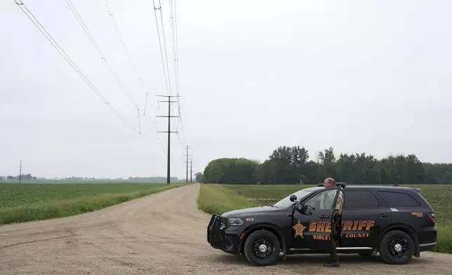A Sibley County Sheriff's deputy blocks off a road leading to the home of Vance Luther Boelter, who officials describe as a person of interest in the killing of Rep. Melissa Hortman and her husband and the shooting of Sen. John Hoffman, near Green Isle, Minn., Saturday, June 14, 2025. (Anthony Souffle/Star Tribune via AP)