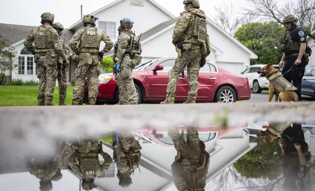Armed FBI agents have a meeting to strategize as they search for an active shooter by sweeping a neighborhood adjacent to the home of Minnesota DFL State Representative Melissa Hortman, in Brooklyn Park, Minn. on Saturday, June 14, 2025. (Alex Kormann/Star Tribune via AP)