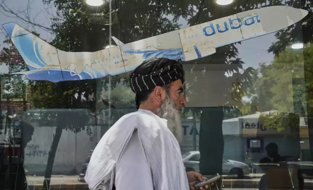 An Afghan man passes in front of an air travel agency in Kabul, Afghanistan, Thursday, June 5, 2025. (AP Photo/Ebrahim Noroozi)