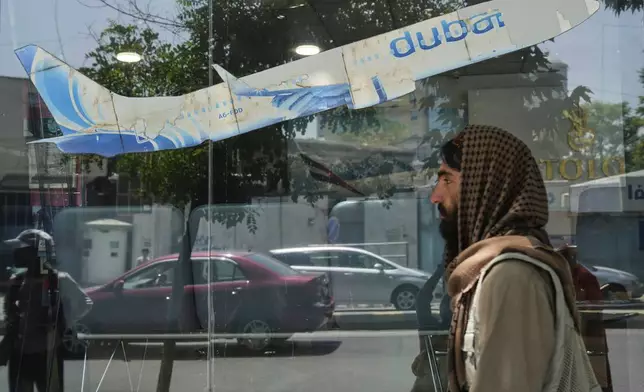 An Afghan person passes in front of an air travel agency in Kabul, Afghanistan, Thursday, June 5, 2025. (AP Photo/Ebrahim Noroozi)