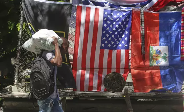 A man walks past a vendor's stall selling U.S. and Haitian flags in Port-au-Prince, Haiti, Thursday, June 5, 2025. (AP Photo/Odelyn Joseph)