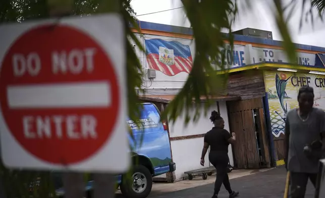 People walk past a Haitian flag painted on the side of Chef Creole's restaurant in Miami's Little Haiti neighborhood, Thursday, June 5, 2025. (AP Photo/Rebecca Blackwell)