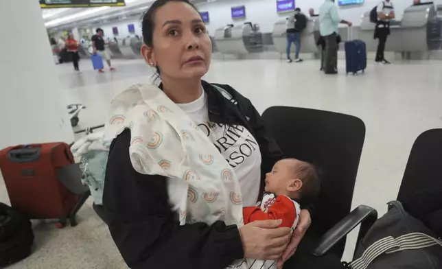 Orelves Gonzalez holds her son Esteban Guilarte, as she listens to updates on her flight back to Venezuela, Thursday, June 5, 2025, at Miami International Airport. Gonzalez has a multiyear tourist visa but is afraid she might not be able to see her family in the U.S. for many years. (AP Photo/Marta Lavandier)