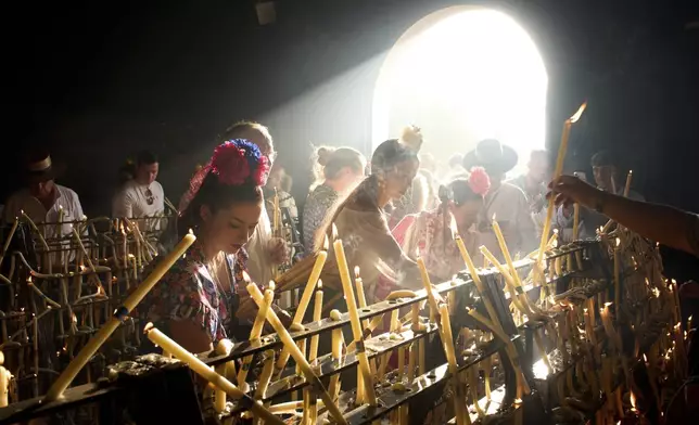 Pilgrims light candles at the shrine of El Rocio near Aznalcázar, Spain, on Saturday June 7, 2025, during the annual pilgrimage in which hundreds of thousands of devotees of the Virgin del Rocio converge in and around the shrine. (AP Photo/Emilio Morenatti)
