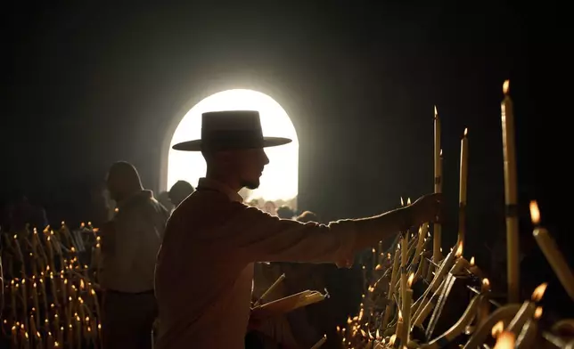 Pilgrims light candles at the shrine of El Rocio near Aznalcázar, Spain, on Saturday June 7, 2025, during the annual pilgrimage in which hundreds of thousands of devotees of the Virgin del Rocio converge in and around the shrine. (AP Photo/Emilio Morenatti)