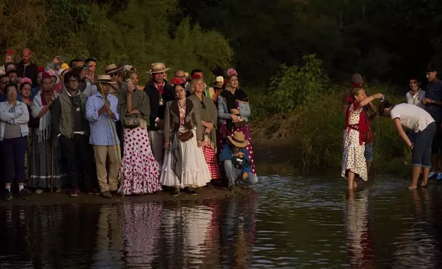 Pilgrims stand at shore of the Quema river near Aznalcázar, Spain, a crucial point in the annual Catholic pilgrimage to the shrine of the Virgin of El Rocio that draws hundreds of thousands of faithful, on June 6, 2025. (AP Photo/Emilio Morenatti)