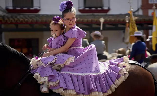 Young pilgrims on horseback, arrive at the shrine of El Rocio near Aznalcázar, Spain, on Saturday June 7, 2025, during the annual pilgrimage in which hundreds of thousands of devotees of the Virgin del Rocio converge in and around the shrine. (AP Photo/Emilio Morenatti)