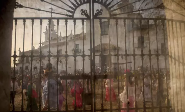 Pilgrims walk next to the shrine of El Rocio near Aznalcázar, Spain, on Saturday June 7, 2025, during the annual pilgrimage in which hundreds of thousands of devotees of the Virgin del Rocio converge in and around the shrine. (AP Photo/Emilio Morenatti)