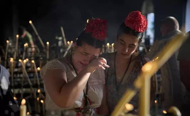 Pilgrims react as they light candles at the shrine of El Rocio near Aznalcázar, Spain, on Saturday June 7, 2025, during the annual pilgrimage in which hundreds of thousands of devotees of the Virgin del Rocio converge in and around the shrine. (AP Photo/Emilio Morenatti)