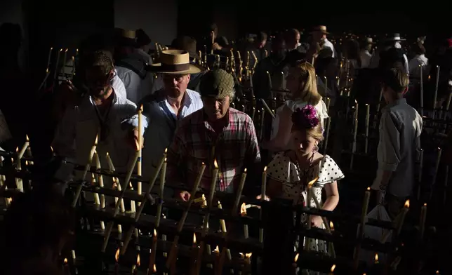 Pilgrims light candles at the shrine of El Rocio near Aznalcázar, Spain, on Saturday June 7, 2025, during the annual pilgrimage in which hundreds of thousands of devotees of the Virgin del Rocio converge in and around the shrine. (AP Photo/Emilio Morenatti)