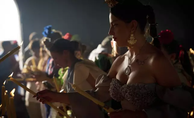 Pilgrims light candles at the shrine of El Rocio near Aznalcázar, Spain, on Saturday June 7, 2025, during the annual pilgrimage in which hundreds of thousands of devotees of the Virgin del Rocio converge in and around the shrine. (AP Photo/Emilio Morenatti)