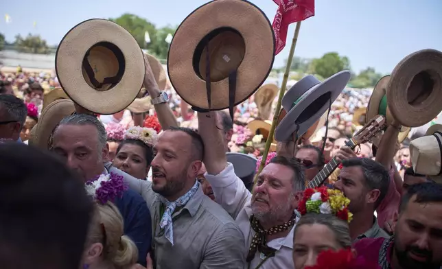 Pilgrims from the Triana brotherhood react as they arrive at the shrine of El Rocio near Aznalcázar, Spain, on Saturday June 7, 2025, during the annual pilgrimage in which hundreds of thousands of devotees of the Virgin del Rocio converge in and around the shrine. (AP Photo/Emilio Morenatti)